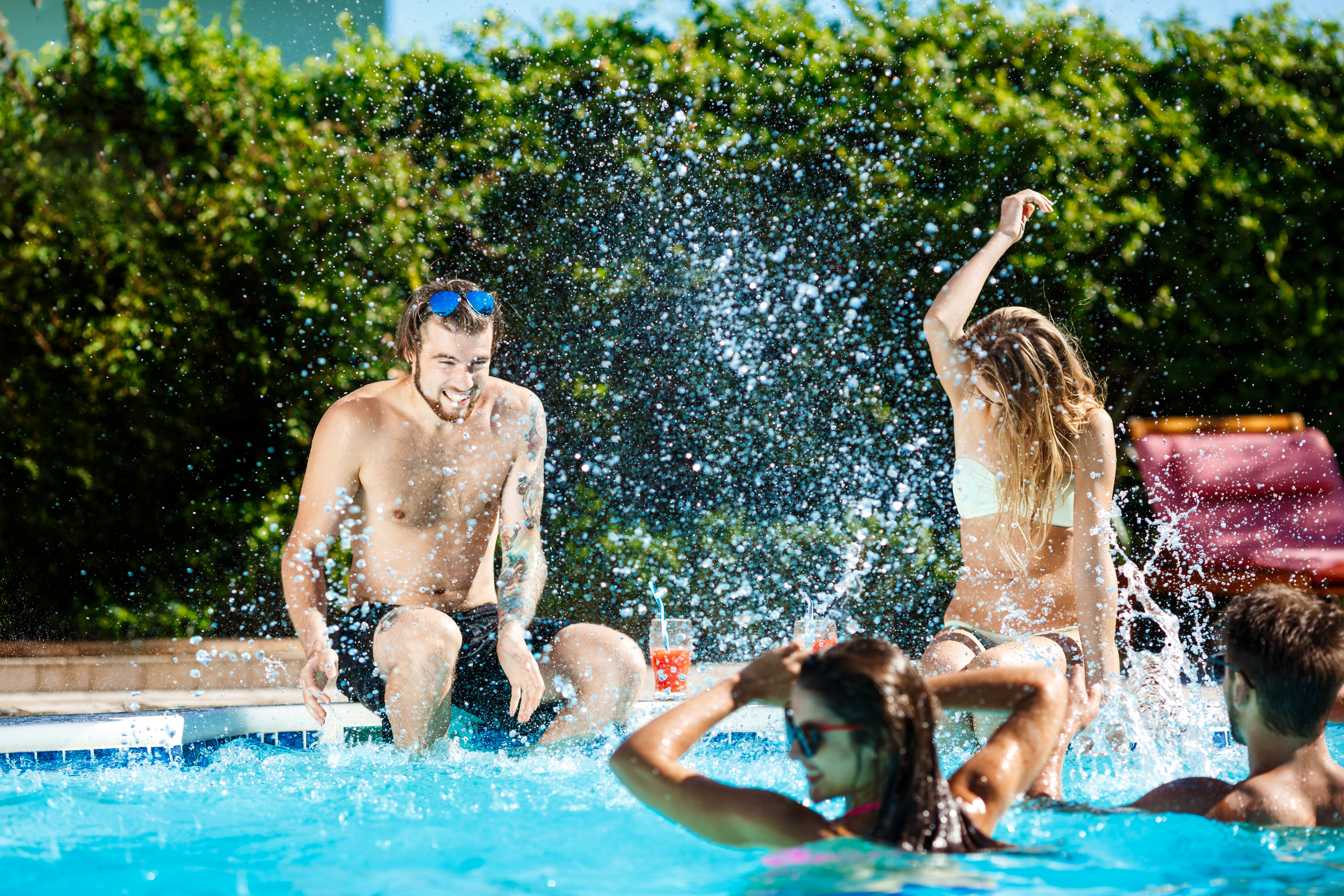 grupo de amigos se divertindo na piscina jogando água para cima